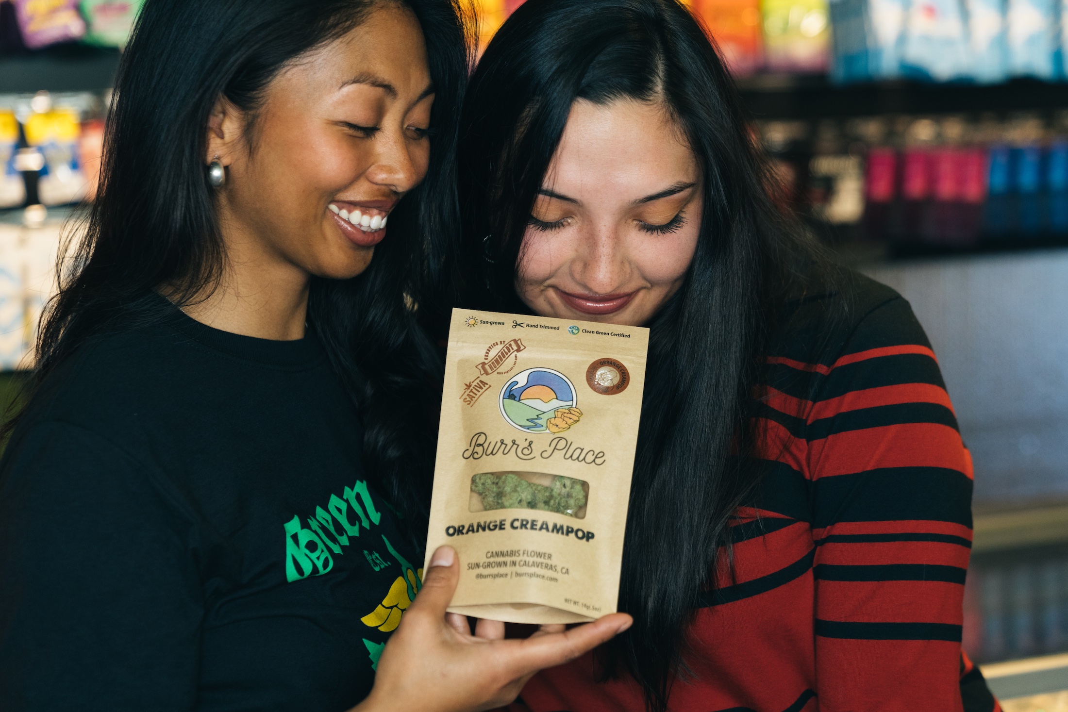 two women smelling packaged orange creampop cannabis flower