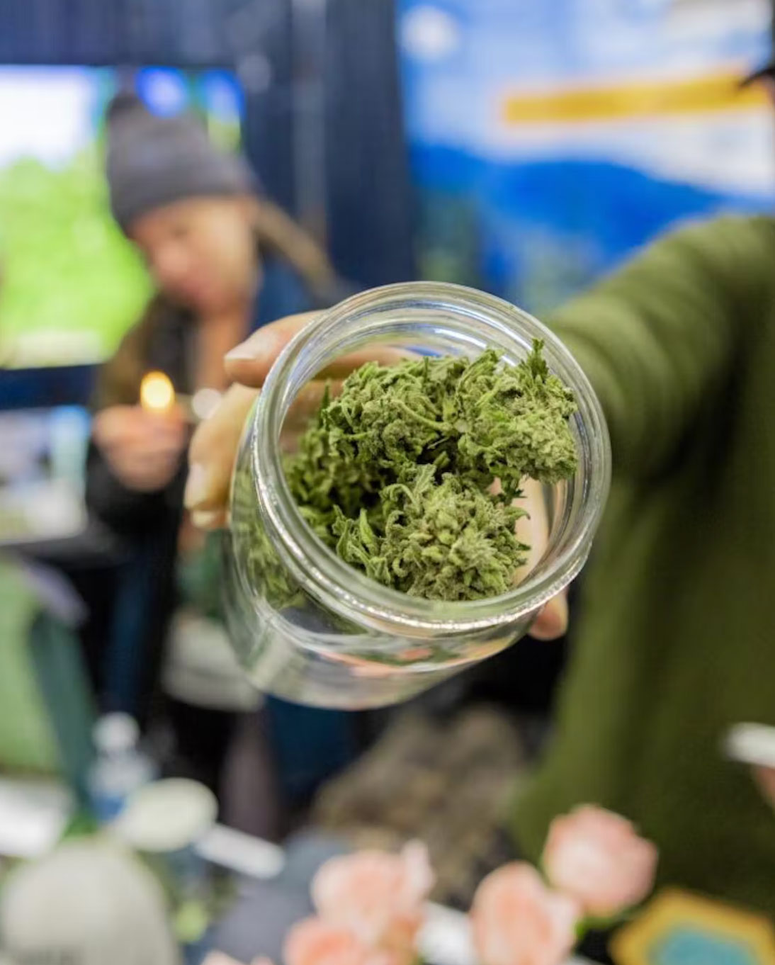 hand holding open jar of cannabis nugs