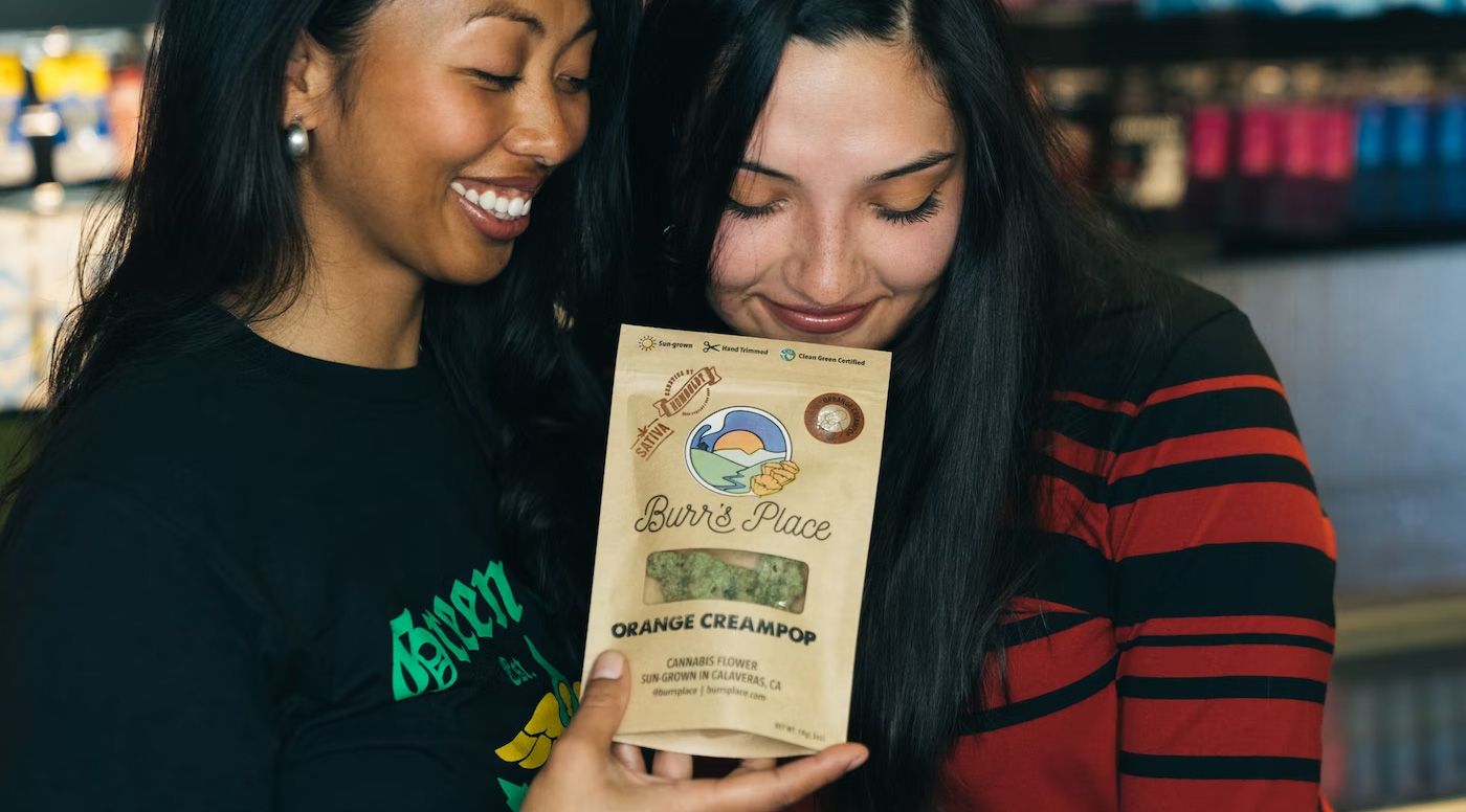 two women smelling package of cannabis nugs