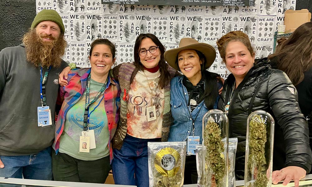 five people smiling with cannabis plants