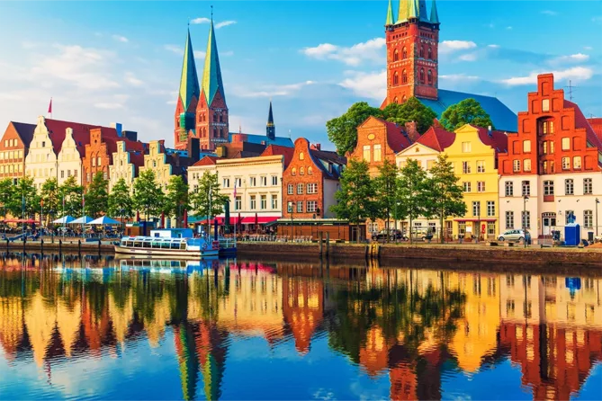 old looking german city on the water with church steeples in the background