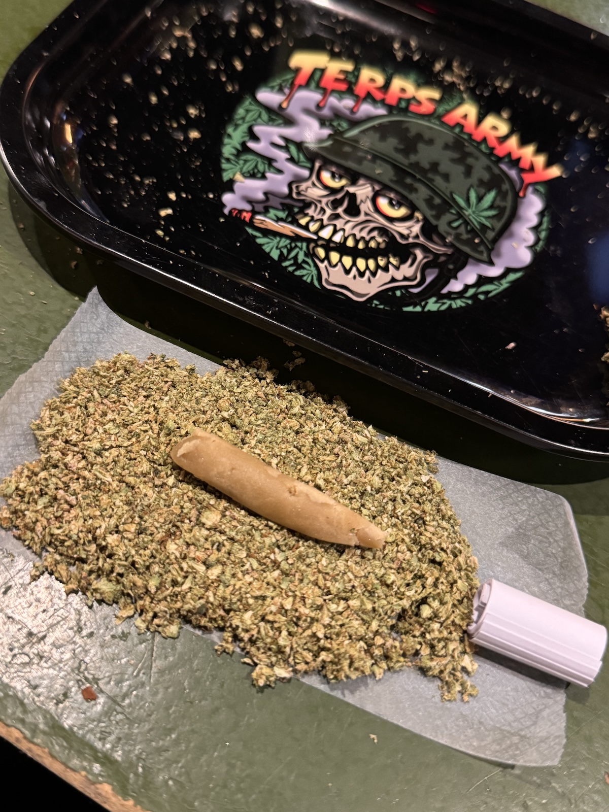 how to roll a hash hole joint showing rolling tray, ground flower, hash, filter, and paper