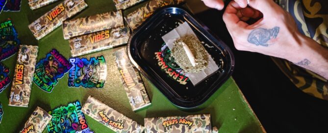 man rolling a hash hole or donut joint with cannabis on a rolling tray tattooed hands
