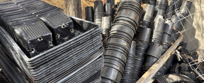 stacks of black plastic grow pots and containers on a farm