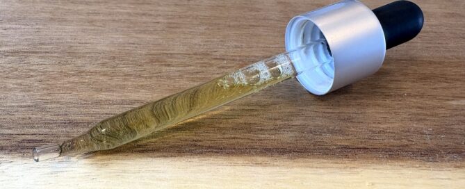 DIY cannabis tincture in a dropper on a wood cutting board