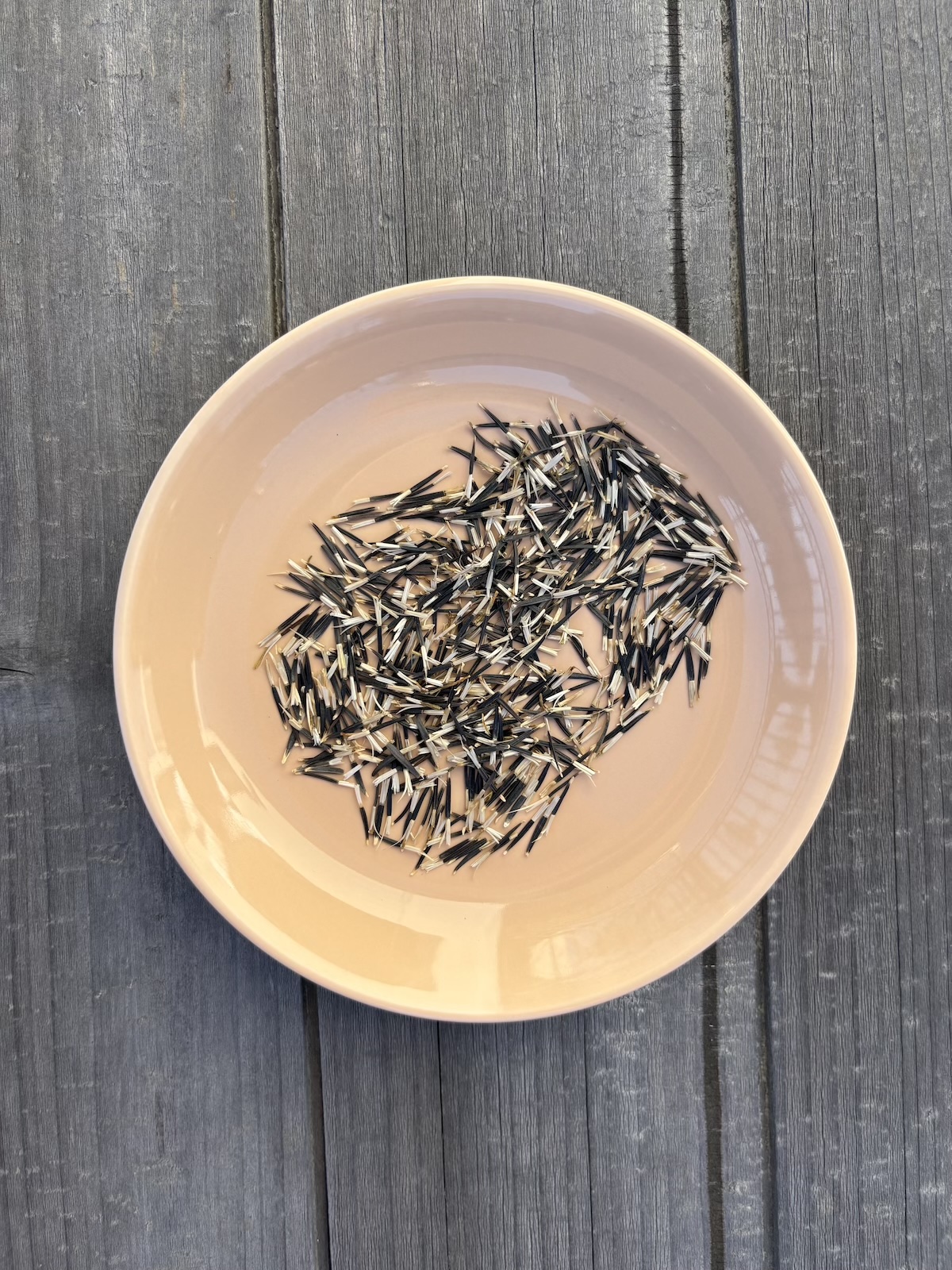 sementes de calêndula num prato cor de pêssego sobre uma mesa de madeira